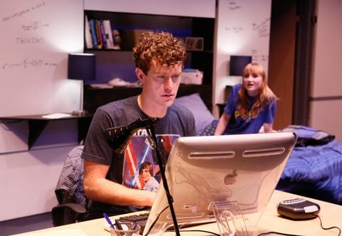 Matt Holzfeind at his computer with Rae Gray behind him